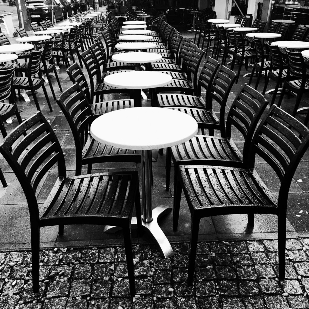 Stühle vor einer Kneipe im Regen