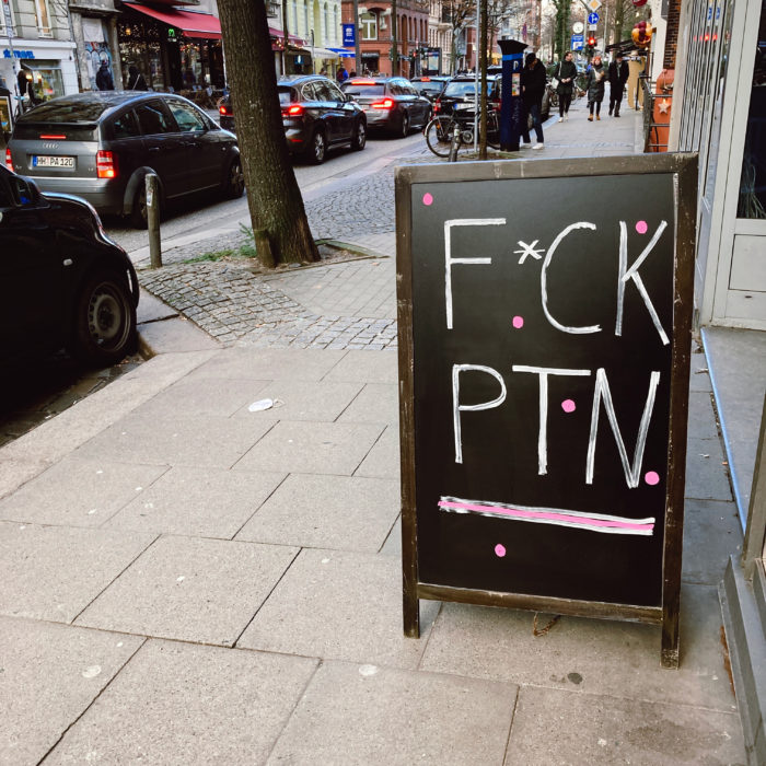 Auf einem Schild vor einem laden steht Fuck P*T*N