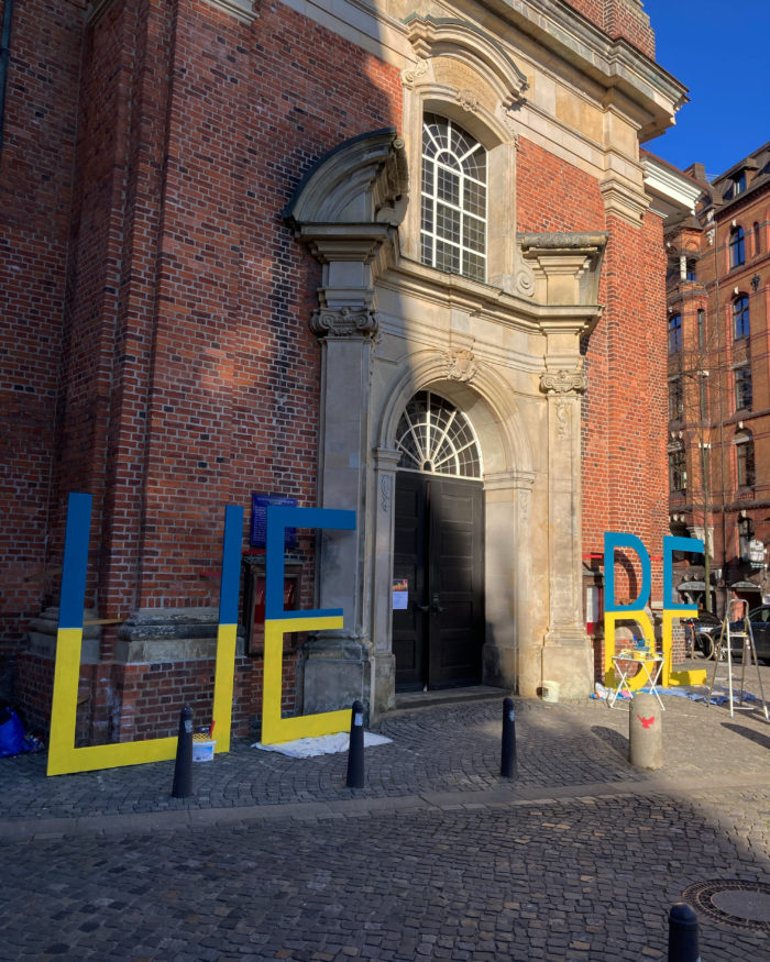 Das Wort Liebe aus riesigen Großbuchstaben neben einem Kirchenportal