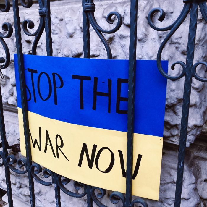 Ein Demo-Pappschild: Stop the war now, blaugelber Hintergrund