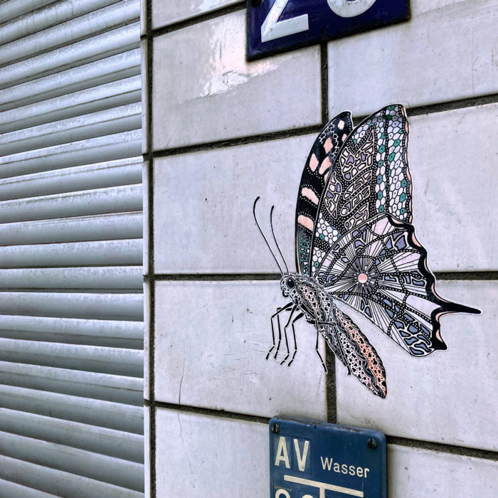 Klebkunst: Ein papierner Schmetterling an einer gekachelten Wand