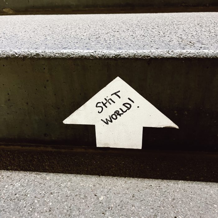 Der Schriftzug "Shit World" auf einer Betontreppenstufe