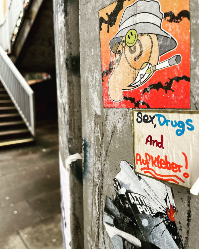 Ein Aufkleber an einer Betonwand in Hammerbrook, Aufschrift: "Sex, Drugs and Aufkleber!"