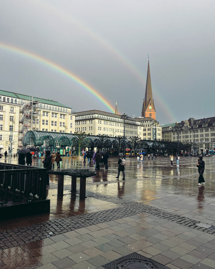 Blick über den Rathausmarkt auf St. Petri bei Regenwetter, am Himmel ein doppelter Regenbogen