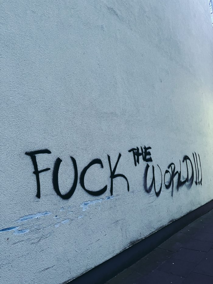 Ein gesprühter Schriftzug an einer Wand: Fuck the world