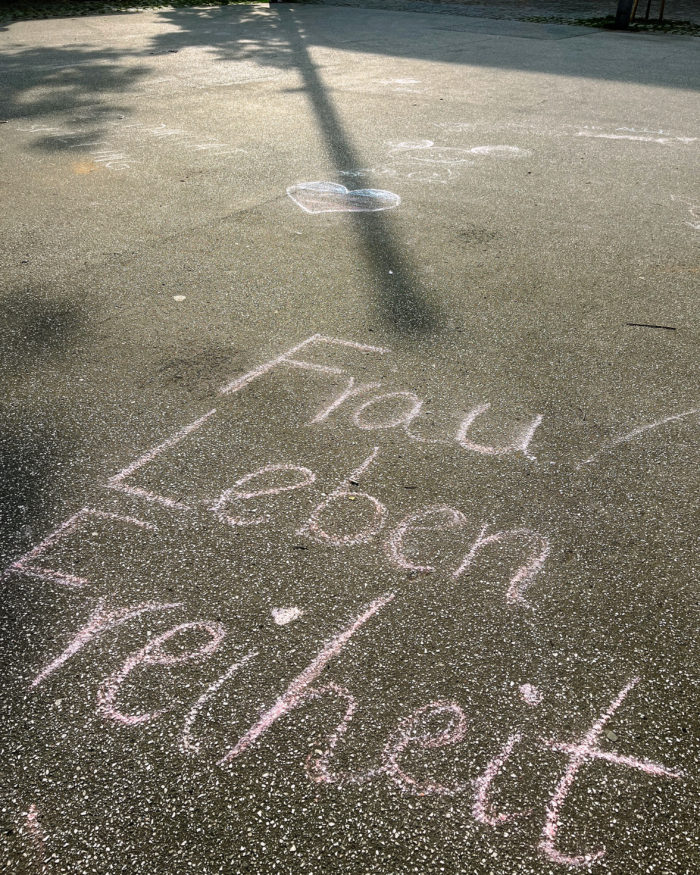 Kreideschrift auf Asphalt: Frau Leben Freiheit