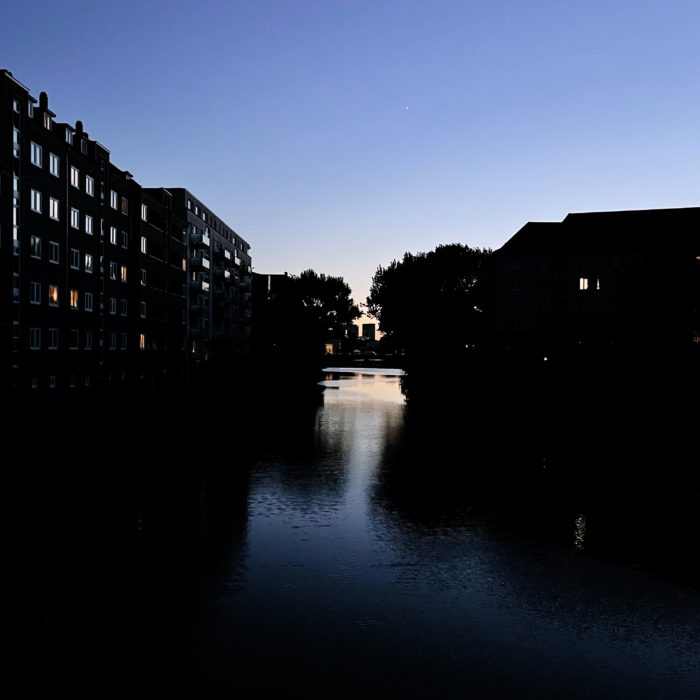 Blick von einer Brücke über ein spätabendliches Fleet in Hamburg-Hamm