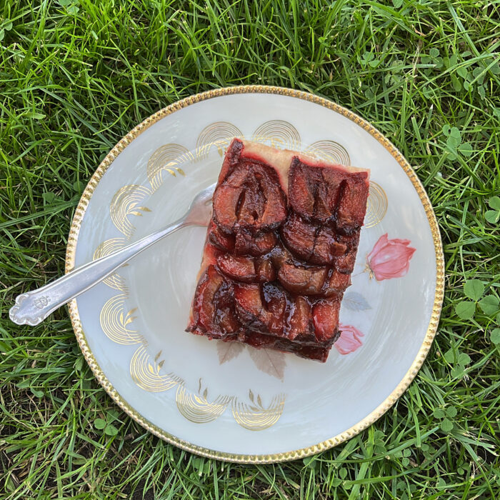 Ein Teller mit Pflaumenkuchen, auf Rasen abgestellt
