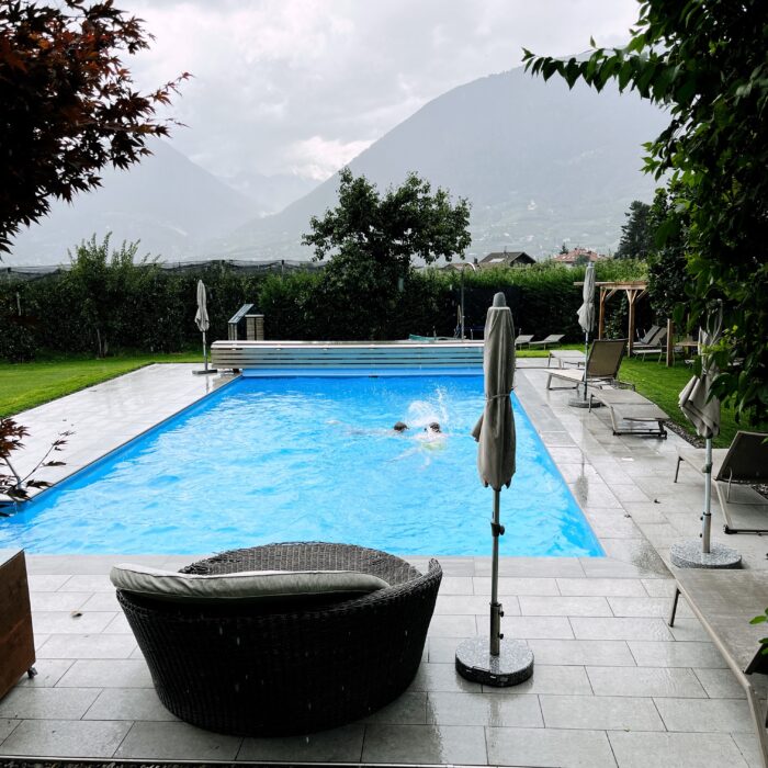 Ein Swimmingpool im Regen, dahinter die Berge