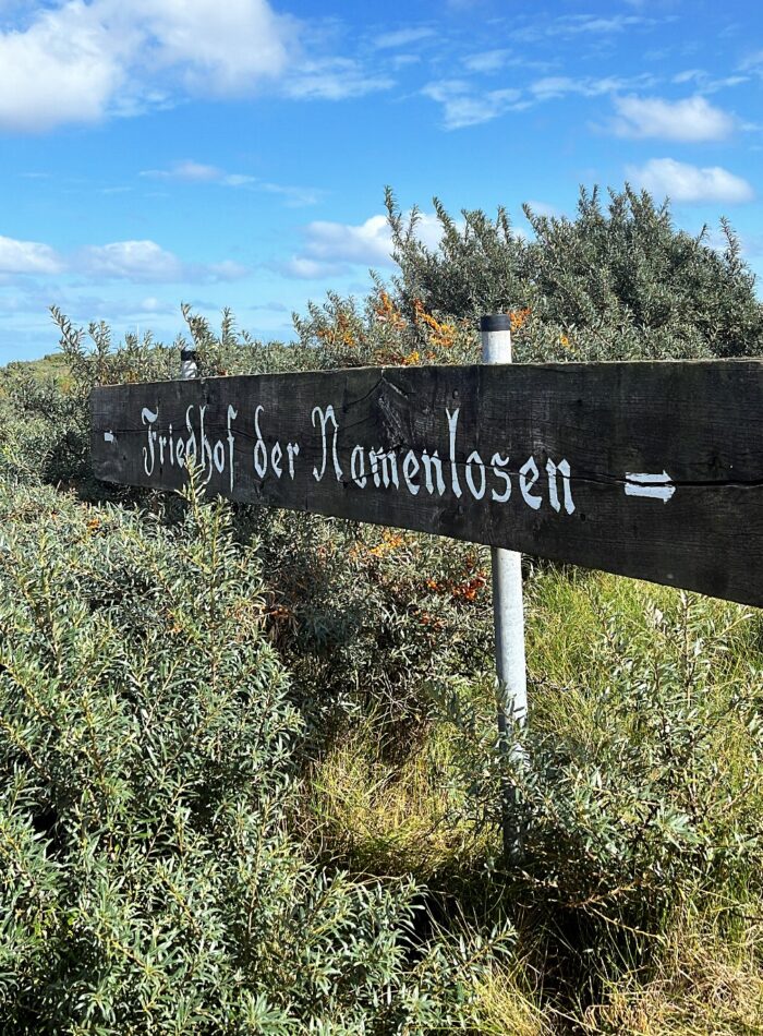 Das Holzschild mit dem Hinweis zum "Friedhof der Namenlosen" auf der Düne vor Helgoland