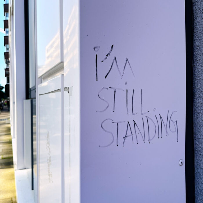 Ein Schriftzug an einem Fensterrahmen von außen: "I'm still standing"