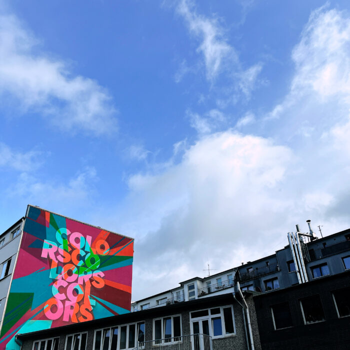 Ein Mural, noch neu und in leuchtenden Farben, bunt und mehrfach der Schriftzug "Colors" vor farbigem Hintergrund