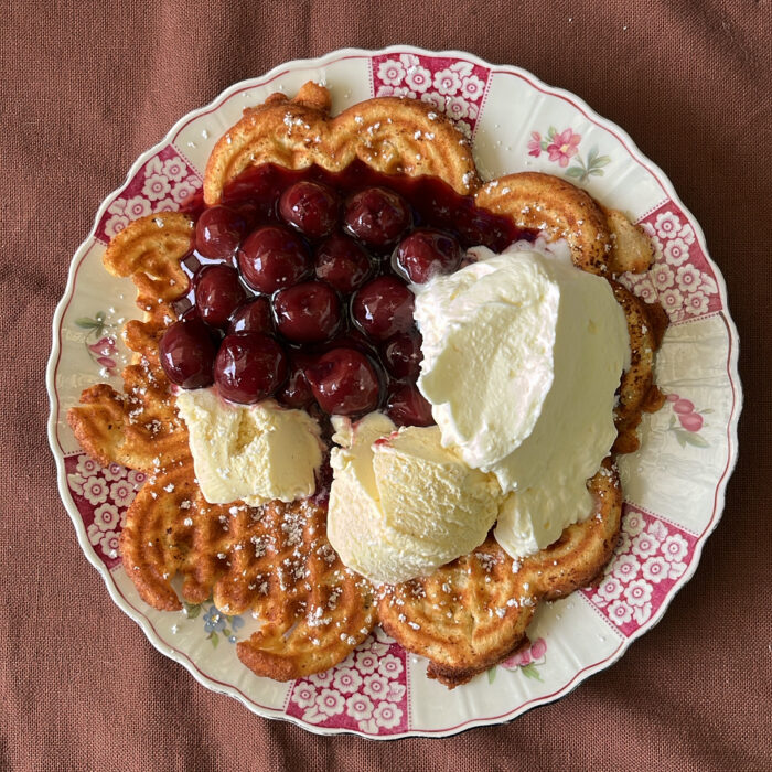 Ein Teller mit Waffeln, Eis, Sahne, Puderzucker