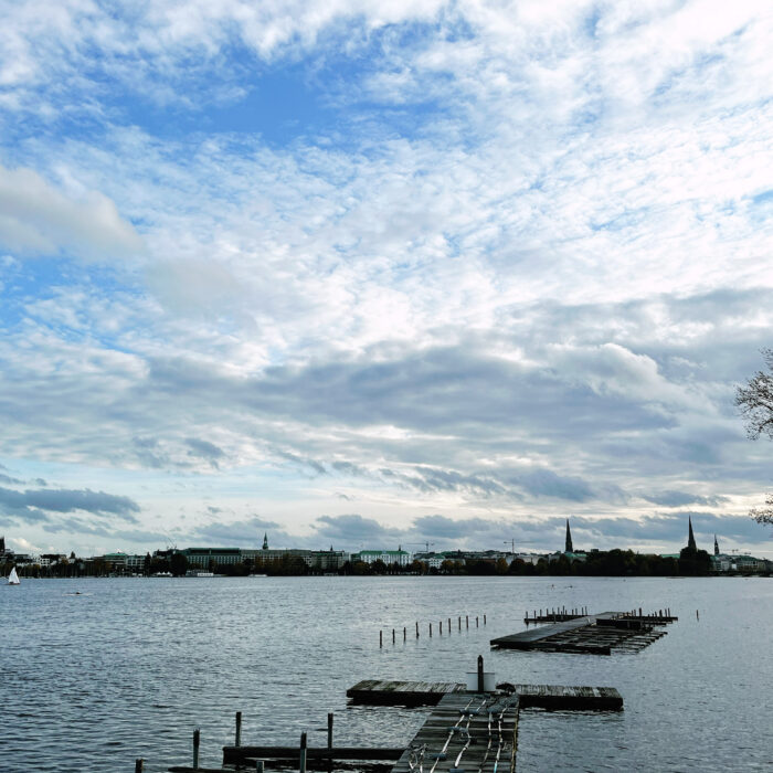 Blick über die Alster von der Harvestehuder Seite aus, Richtung Sankt Georg. Im Vordergrund leere Stege auf dem Wasser.
