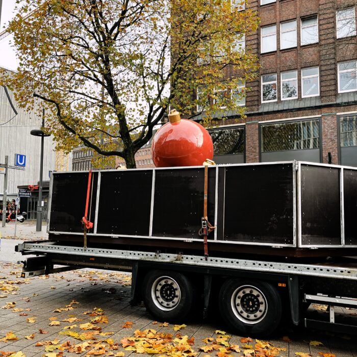 Eine riesige rote Christbaumkugel auf einem LKW-Anhänger