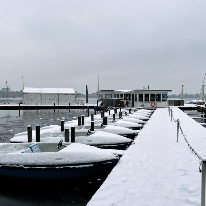Eingeschneite Tretboote an einem Steg an der Außenalster