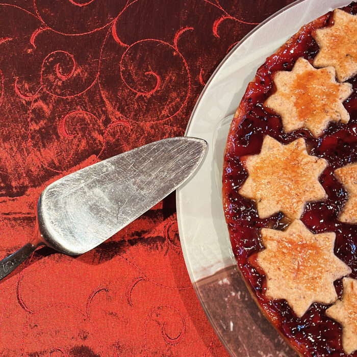 Festlich aussehender Kuchen auf einem Teller auf dunkelroter Tischdecke