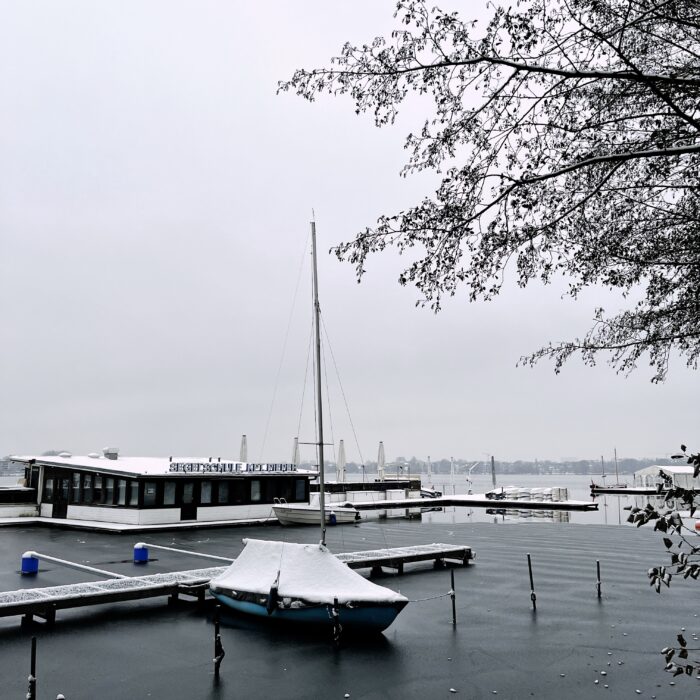 Ein eingeschneites Segelboot unter einer Persenning an der Alster