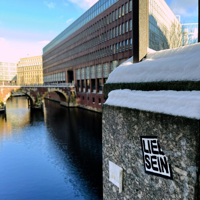 Blick von der Michaelisbrücke über das Fleet, im Vordergrund an einem Pfeiler ein Aufkleber: "Lieb sein"