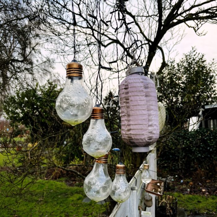 Angeschmuddelte Lampions weit jenseits ihrer Buntheit und tropfnasse Lichterketten hängen im Garten