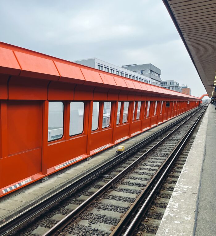Die rote Außenwand der S-Bahnstation Hammerrbook, dynamische Perspektiv-Wirkung durch die Linien von Gleisen und Wand