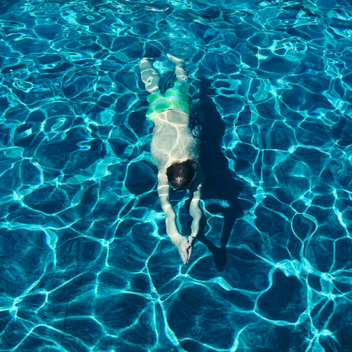 Ein tauchender Sohn im Pool, von oben fotografiert