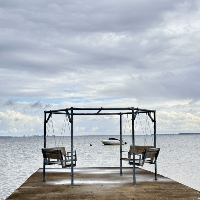 Ein Gestänge mit aufgehängten, leeren Schaukelbänken auf einem Steg an der Ostsee