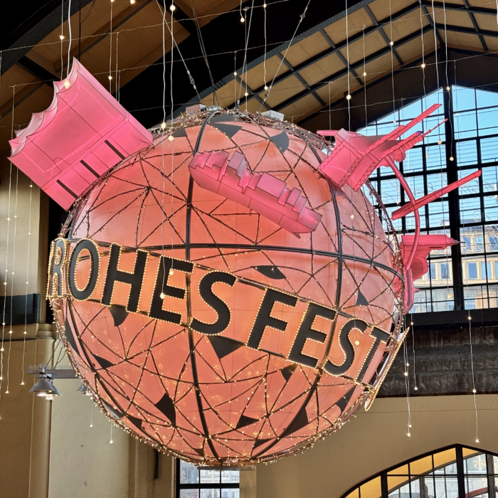 Ein Deko-Element im Hamburger Hauptbahnhof, eine große Kugel unter der Decke, auf der ringsum "Frohes Fest" steht, wovon aber nur "Rohes Fest" zu lesen ist