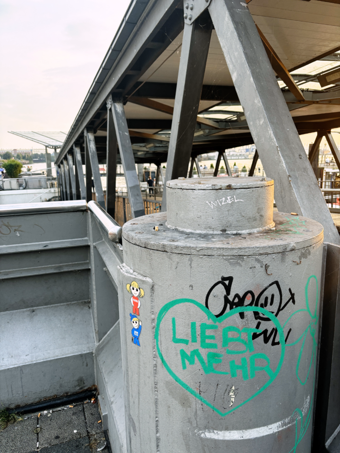 Auf einem Pfosten an den Landungsbrücken ein Graffiti-Herz, in dem "Liebt mehr" steht