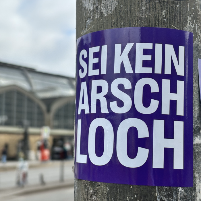 Ein Aufkleber an einem Ampelmast: Sei kein Arschloch