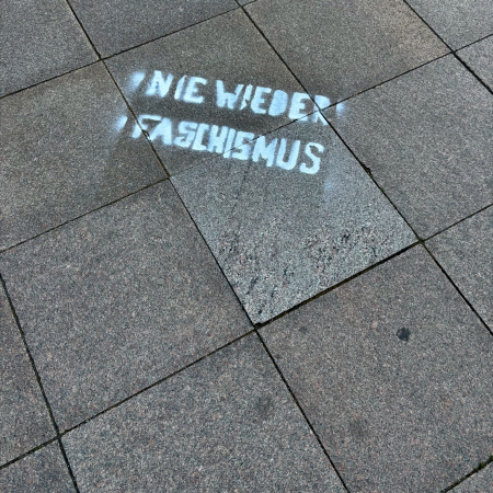 Weiße Schrift auf dem Pflaster: Nie wieder Faschismus