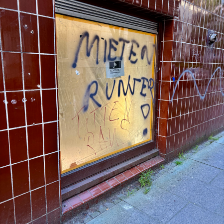 Ein von innen mit Papier abgeklebtes Schaufenster, auf die Scheibe wurde "Mieten runter, Titten raus!" geschrieben