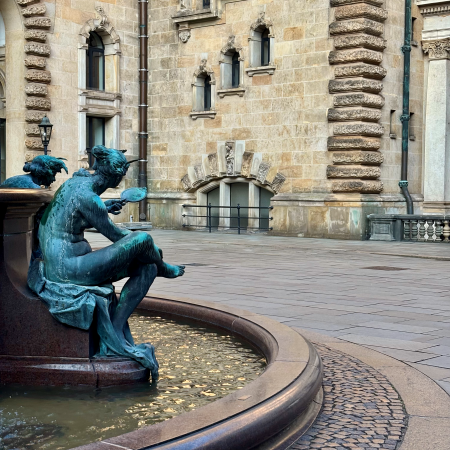 Der Brunnen im Innenhof des Hamburger Rathauses, eine der Figuren in Nahaufnahme und von hinten