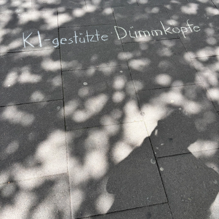 Kreideschrift auf dem Pflaster: "KI-gestützte Dummköpfe"