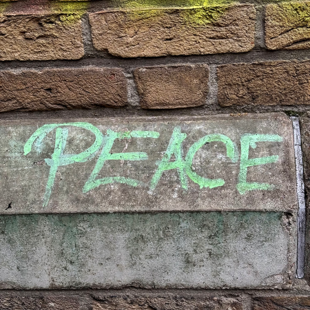 Hellgrüne Schrift an einer Fassade: Peace