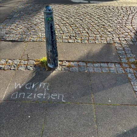 Kreideschrift auf dem Pflaster: "Warm anziehen"