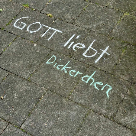 Kreideschrift auf dem Pflaster "Gott liebt Dickerchen"