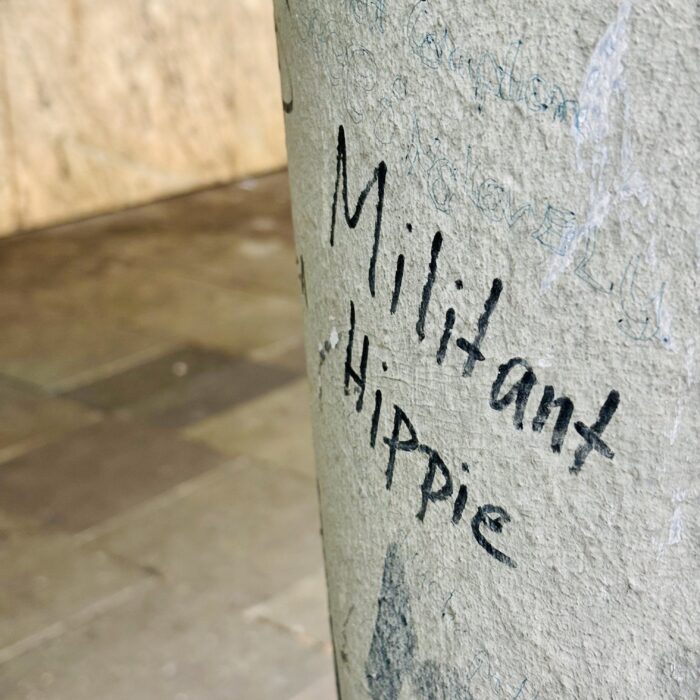 Schrift mit Edding auf einem Pfeiler: "Miltant Hippie"