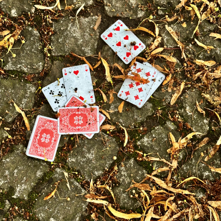Heruntergefallene Spielkarten auf dem Pflaster, daneben schon herbstliches Laub