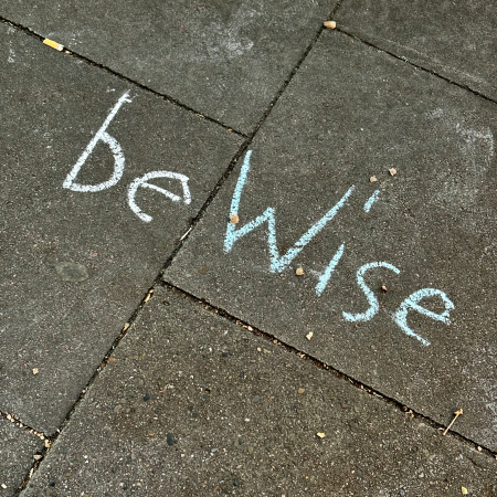 Kreideschrift auf dem Pflaster: "Be Wise"