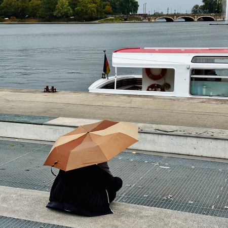 Jemand sitzt unter einem Schirm an Anleger Jungfernstieg und sieht auf die Binnenalster