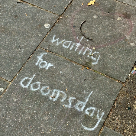 Kreideschrift auf dem Pflaster: Waiting for doomsday