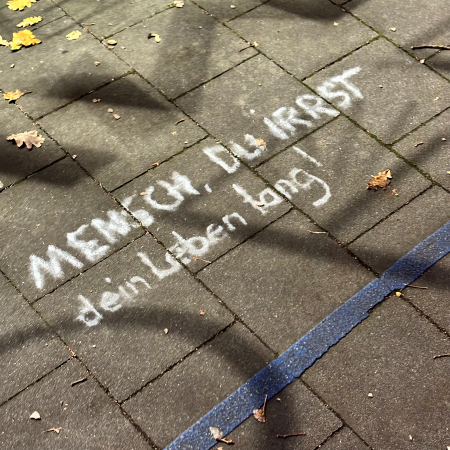 Kreideschrift auf dem Pflaster: "Mensch, du irrst ein Leben lang"