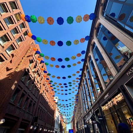 Der Neue Wall, an aufgespannten Leinen hängen sehr viele bunte Regenschirme als Herbstdeko über der Straße