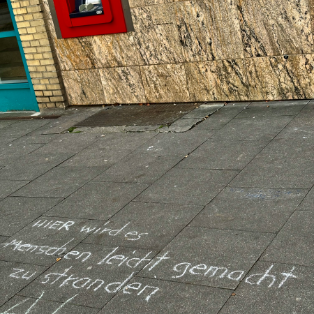 Kreideschrift auf dem Pflaster: Hier wird es Menschen leicht gemacht zu stranden