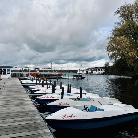 Tretboote an einem Steg an der Außenalster, unter grauem Himmel bei aufziehenden Sturm