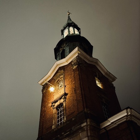 Der Turm der Dreieinigkeitskirche bei Nachtm mit leuchtendem Weihnachtsstern am Fenster