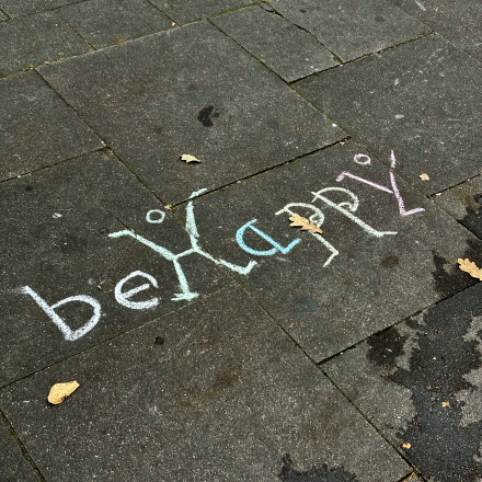 Kreideschrift auf dem Pflaster: Be Happy