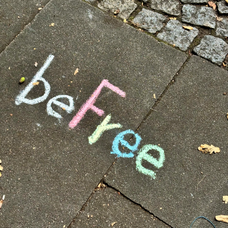 Kreideschrift auf dem Pflaster: Be Free