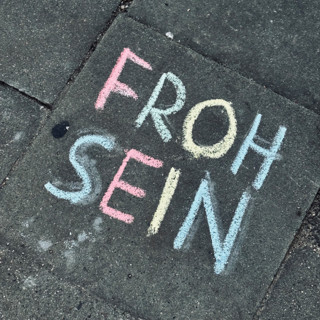 Kreideschrift auf dem Pflaster: Froh sein